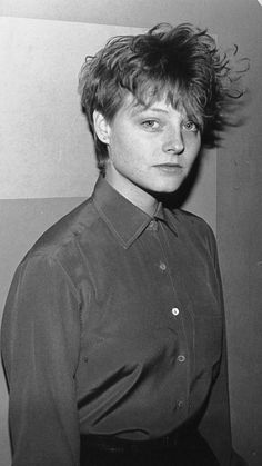 a black and white photo of a woman wearing a shirt with her hair blowing in the wind