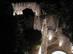 an aerial view of a building at night with lights on the side and trees surrounding it