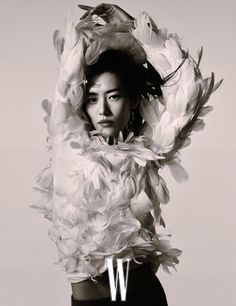 a woman is posing for a photo with feathers on her head and the word w above her head