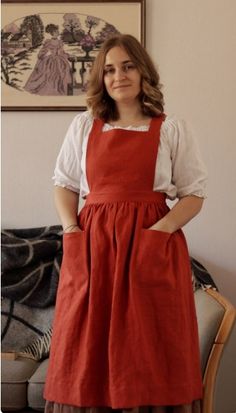 a woman standing in front of a couch wearing an apron