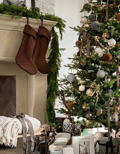 a decorated christmas tree with stockings hanging from it's sides in front of a fireplace