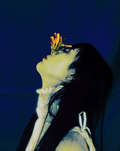 a woman with long black hair and a flower on her head is looking up at the sky