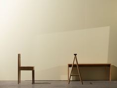 two wooden chairs sitting next to each other in front of a white wall and floor