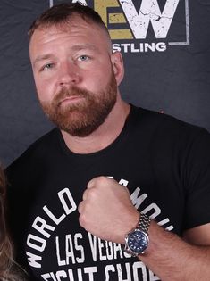 a man standing next to a woman in front of a black backdrop with the words world wrestling on it