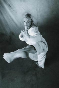 a black and white photo of a woman in the air with her legs spread out