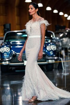 a woman in a white dress standing next to a car