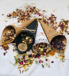 three cones filled with different types of flowers on top of a white cloth covered table