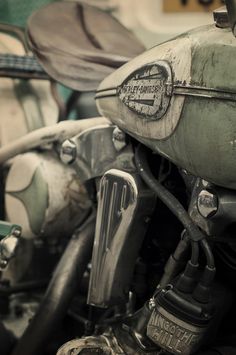 an old green motorcycle parked next to other motorcycles