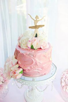 a pink cake with white flowers and a figure on top