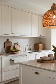 a kitchen with white cabinets and an island in front of the counter top is lit by a hanging light