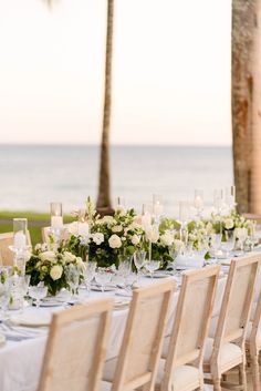 a long table is set with white flowers and greenery for an outdoor wedding reception