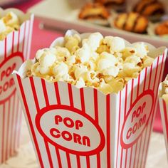 three red and white striped popcorn bags with the word pop corn on them sitting on a table