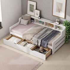 a bed with drawers underneath it in a room next to a rug and potted plant