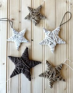 three star ornaments are hanging from string on a wooden surface, one is black and the other is white