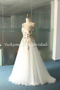 a white wedding dress on display in a glass case with blue carpet and wall behind it