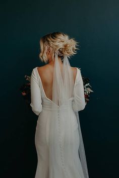 the back of a bride's wedding dress, with her veil draped over her shoulder