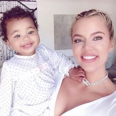 a woman holding a child in her arms and smiling at the camera while standing next to stairs