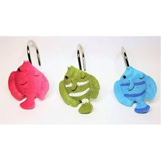 three different colored fish shaped key fobs hanging from hooks on a white background