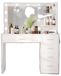 a white vanity with lots of beauty products on it and a plant in the mirror