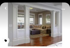 a living room filled with furniture next to a window covered in white columns and wood flooring