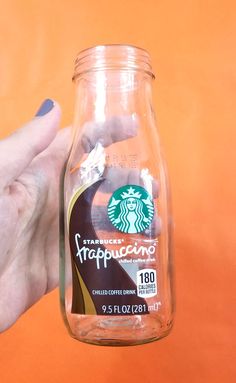 a person holding up a starbucks cup in a jar