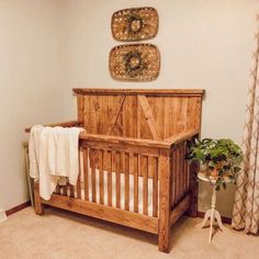 a wooden crib in the corner of a room next to a potted plant