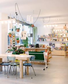 a room filled with lots of tables and chairs next to a book shelf full of books