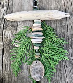 a piece of driftwood with stones and green leaves hanging from it's side