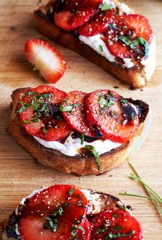 two slices of toast with strawberries and cream on top, sitting on a cutting board