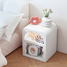 a white box with some items on top of it next to a bed and pillows