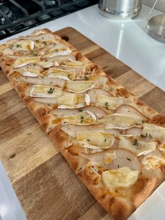 a pizza sitting on top of a wooden cutting board next to a stove burner