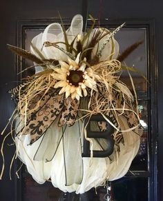 a decorated front door hanger with a sunflower and ribbon hanging from it's side