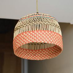 an orange and white woven light fixture hanging from a ceiling in a home or office