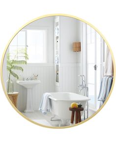 a white bath tub sitting next to a sink in a bathroom under a mirror with gold trim