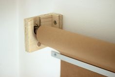 a roll of toilet paper is hanging on the wall next to a wooden roller holder