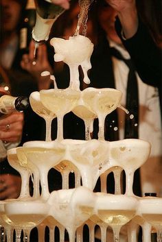 a group of people standing around a fountain filled with wine bottles and ice cubes