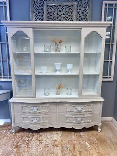 a white china cabinet with glass doors and drawers