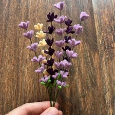 a hand is holding some fake flowers on a table