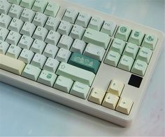 a computer keyboard sitting on top of a white table next to a blue and pink wall