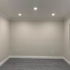 an empty room with white walls and wood flooring is seen in this image, there are two mirrors on the wall