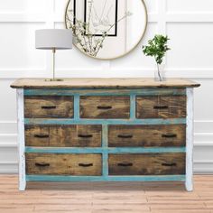 an old dresser with drawers and a mirror on the wall above it in a white room