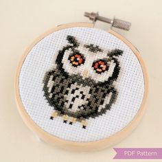 an owl cross stitched on to a white wall hanging from a wooden hoop frame