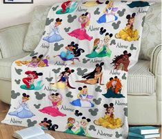 a blanket with disney characters on it sitting in front of a white chair and book