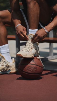 a man tying his shoes on top of a basketball