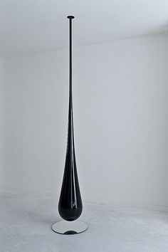 a tall black vase sitting on top of a white floor next to a window in an empty room