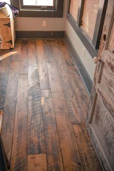 an empty room with wood flooring and a wooden door in the center, looking out to outside