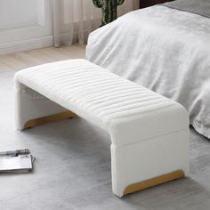 a white bench sitting on the floor next to a bed