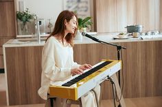 a woman is sitting at a keyboard in front of a microphone and looking into the distance