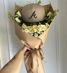 a baseball cap is wrapped in brown paper with daisies and flowers on it, as well as the letter a