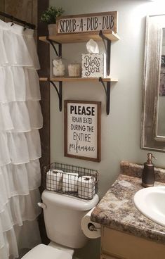 a white toilet sitting next to a bathroom sink under a mirror with shelves above it